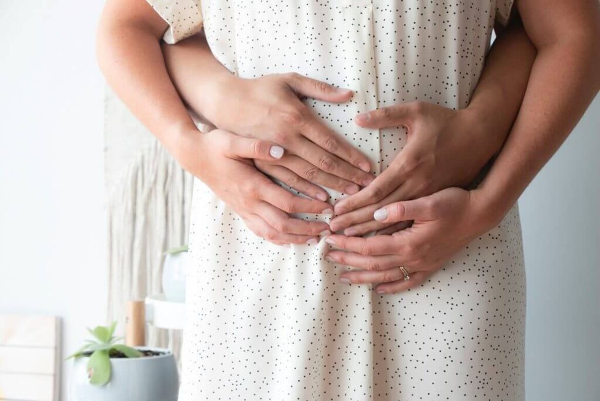 Hände auf dem Bauch einer schwangeren Frau